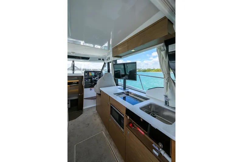 Slide: The Image of Interior of 2022 Jeanneau NC Weekender 1095 Fly, featuring helm, kitchen, and scenic water view. - 24
