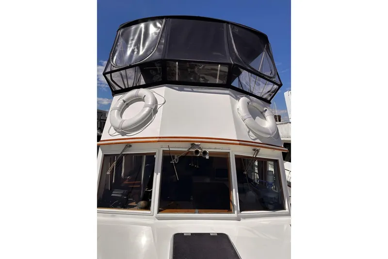 Slide: The Image of 1994 Grand Banks 42 Classic yacht with lifebuoys and enclosed flybridge under clear blue sky. - 10