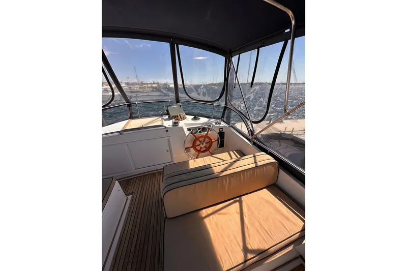 Slide: The Image of 1994 Grand Banks 42 Classic yacht helm with wooden wheel and cushioned seating. - 14