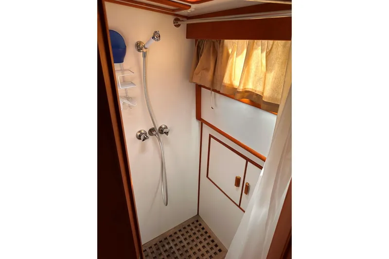 Slide: The Image of Shower area in a 1994 Grand Banks 42 Classic yacht, featuring wooden accents and curtain. - 32