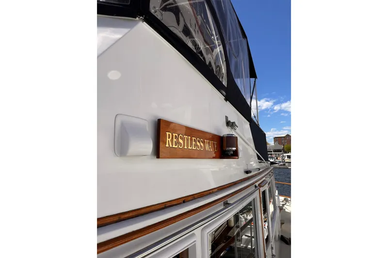 Slide: The Image of 1994 Grand Banks 42 Classic yacht with "Restless Wave" nameplate, docked under clear blue sky. - 6