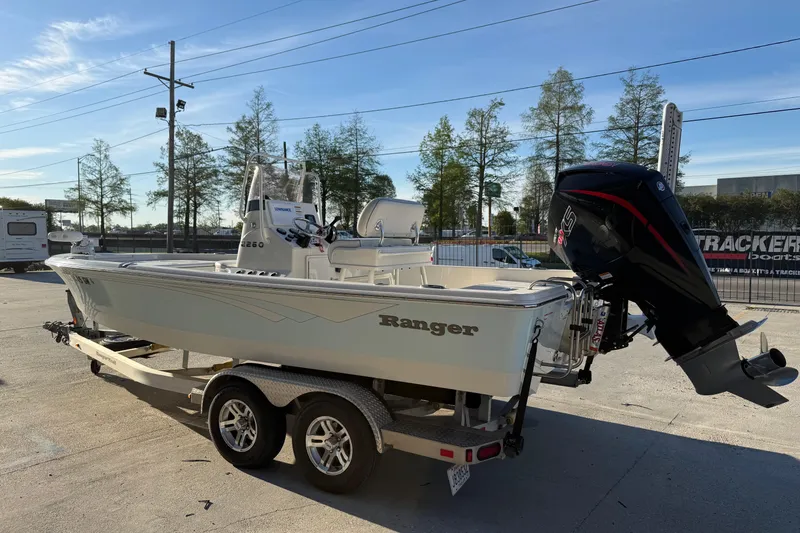 Slide: The Image of 2021 Ranger 2260 Bay Ranger boat on trailer with outboard motor in sunny outdoor setting. - 2