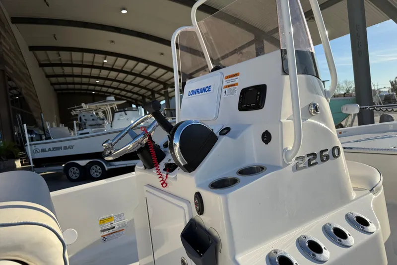 Slide: The Image of 2021 Ranger 2260 Bay Ranger boat console with steering wheel and controls in a marina. - 9