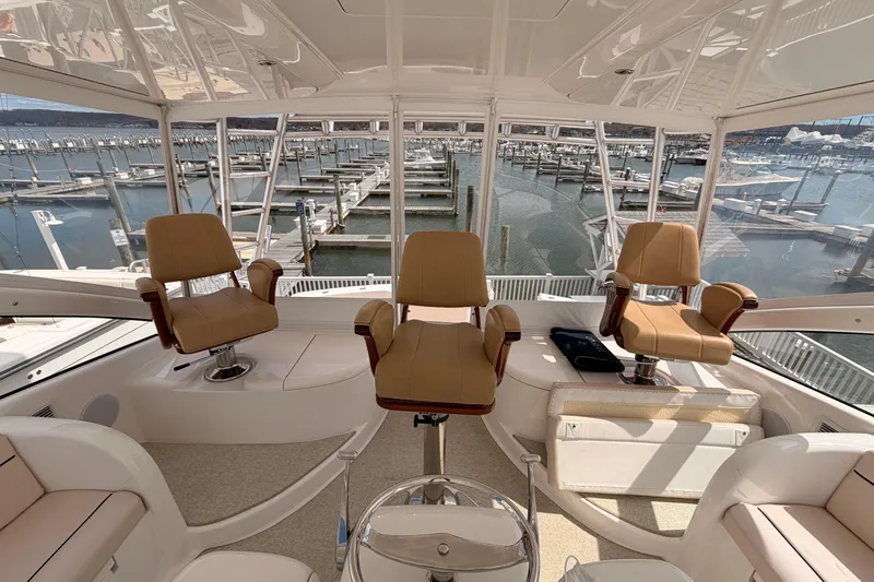 Slide: The Image of Interior view of 2015 Viking 42 Open yacht with three captain's chairs overlooking marina. - 10