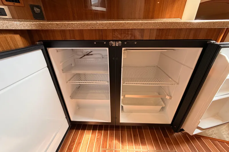 Slide: The Image of Open refrigerator in 2015 Viking 42 Open yacht interior, featuring wooden cabinetry and flooring. - 23