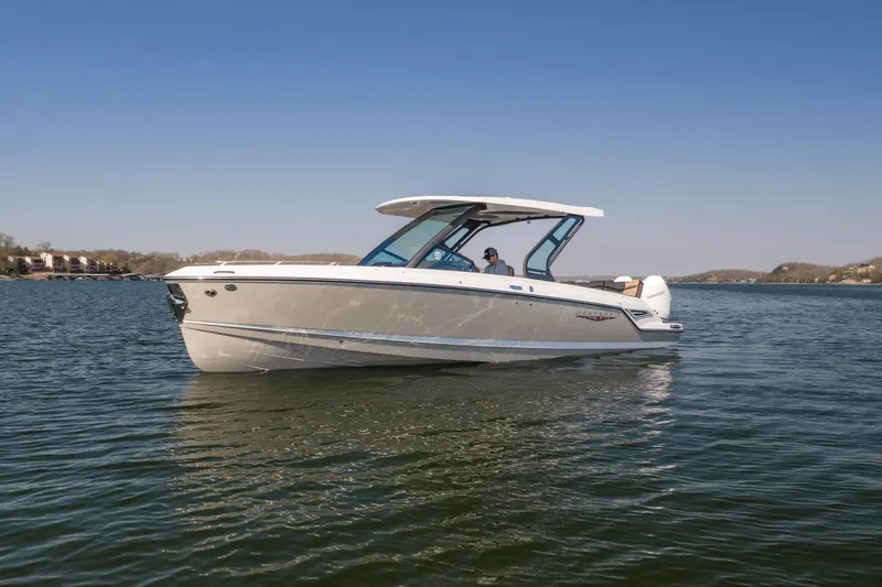 The Image of 2026 Monterey Elite 30 OB boat cruising on a calm lake under clear blue skies. - 1