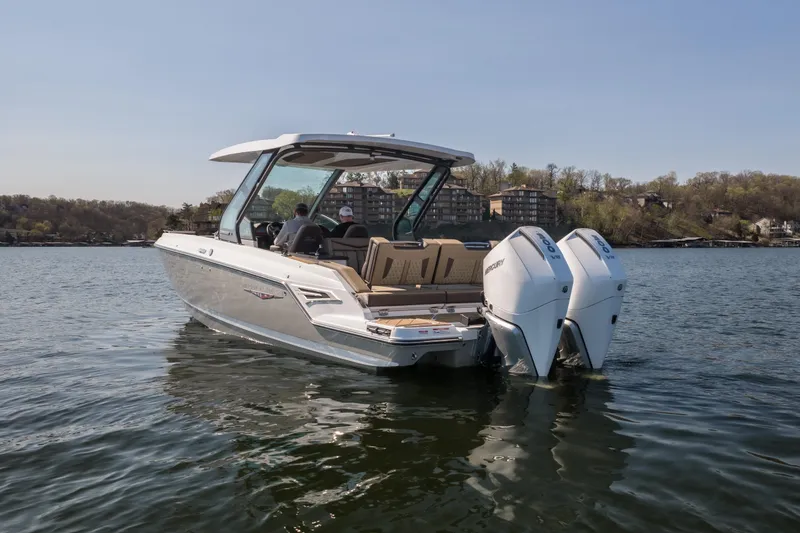 Slide: The Image of 2026 Monterey Elite 30 OB boat on a calm lake with twin outboard engines. - 6