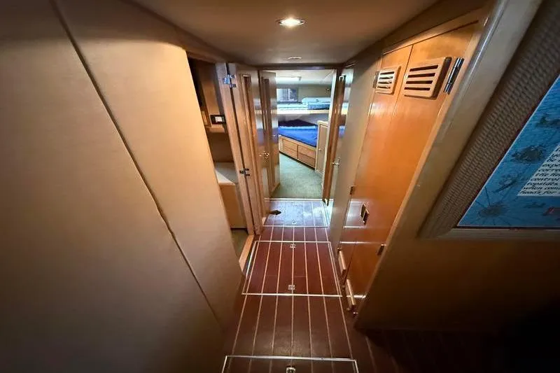 Slide: The Image of Interior hallway of a 1996 Bertram 50 Convertible yacht, featuring wood paneling and cozy lighting. - 22