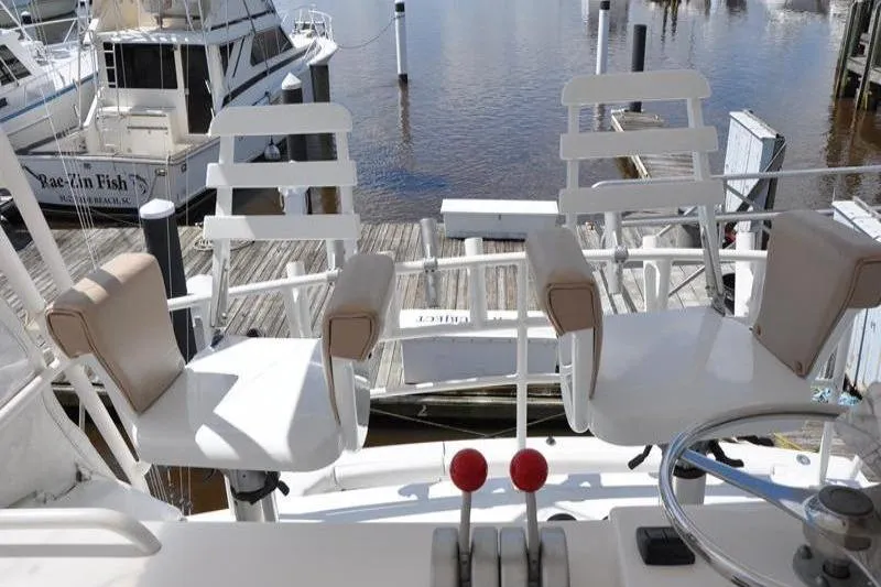 Slide: The Image of Bertram 50 Convertible 1996 yacht helm with dual captain chairs and marina view. - 32