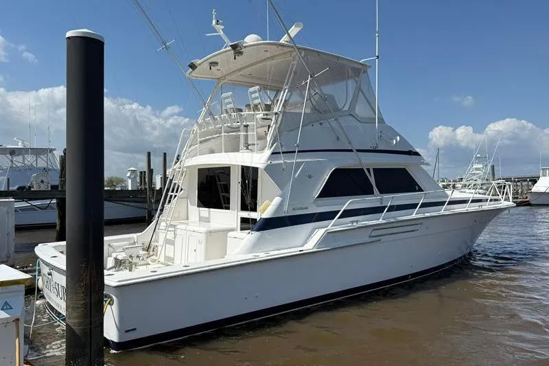 Slide: The Image of 1996 Bertram 50 Convertible yacht docked at marina under clear blue sky. - 4