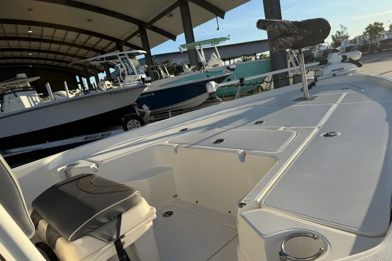 Slide: The Image of 2019 Skeeter SX240 boat deck with seating and storage, parked in a covered marina. - 10