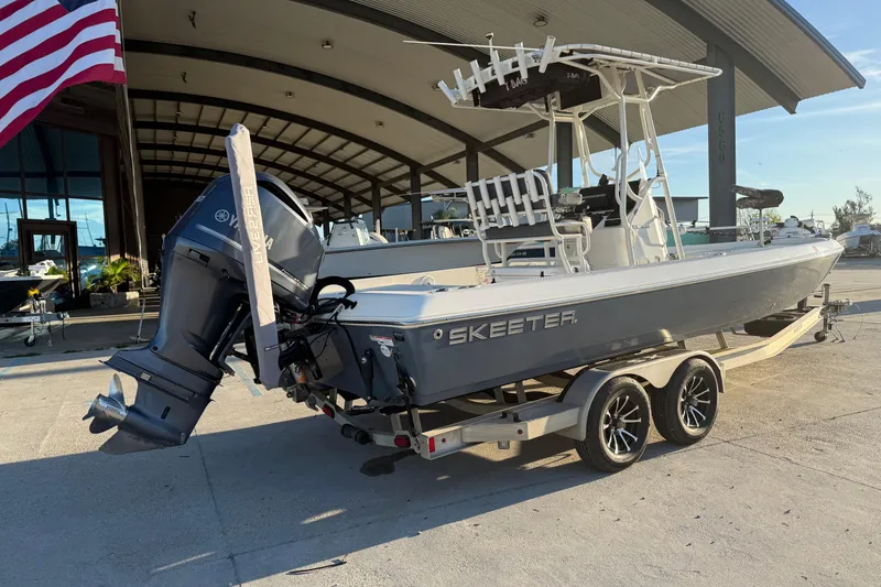 Slide: The Image of 2019 Skeeter SX240 boat on trailer, parked outdoors near a large building. - 8