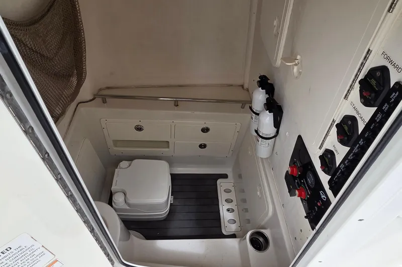 Slide: The Image of Interior of 2016 Sailfish 320 CC boat featuring a compact marine toilet and control panel. - 13