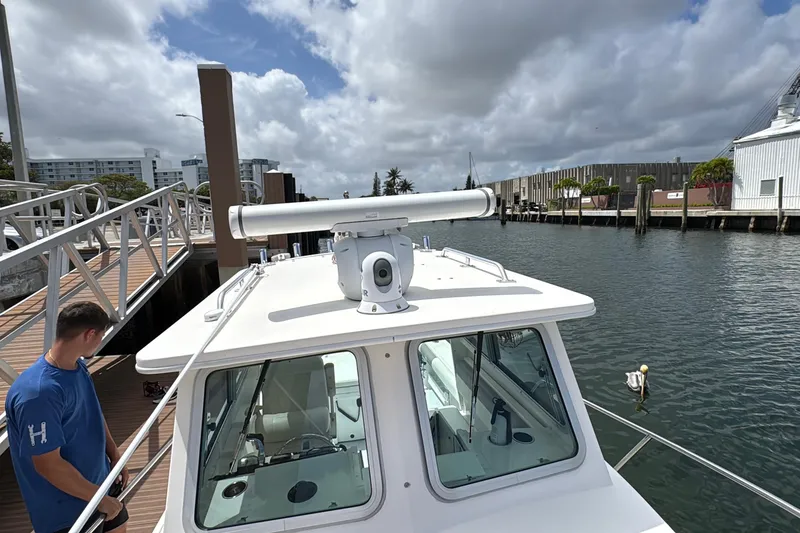 Slide: The Image of 2019 Steiger Craft 255 Miami boat docked, featuring radar equipment and a person on deck. - 26