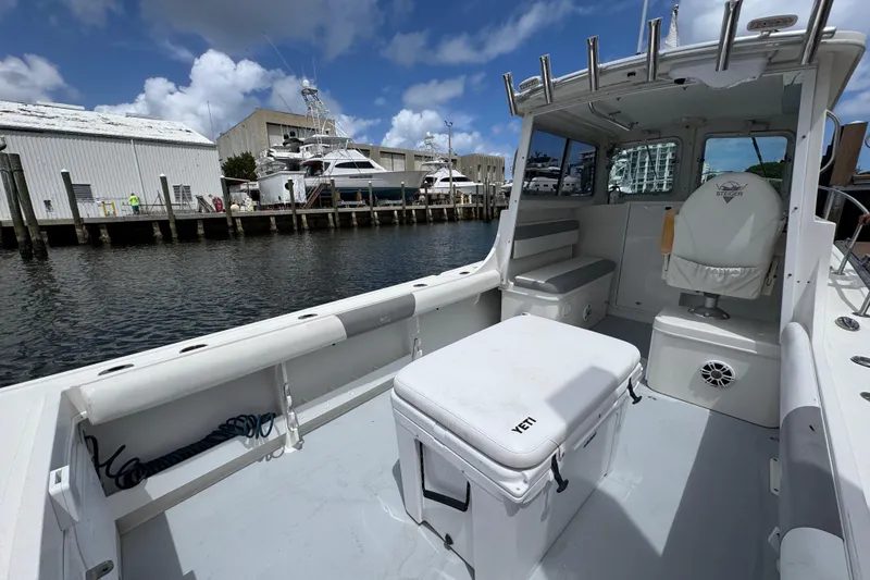 Slide: The Image of 2019 Steiger Craft 255 Miami boat interior at marina, featuring seating and storage. - 9