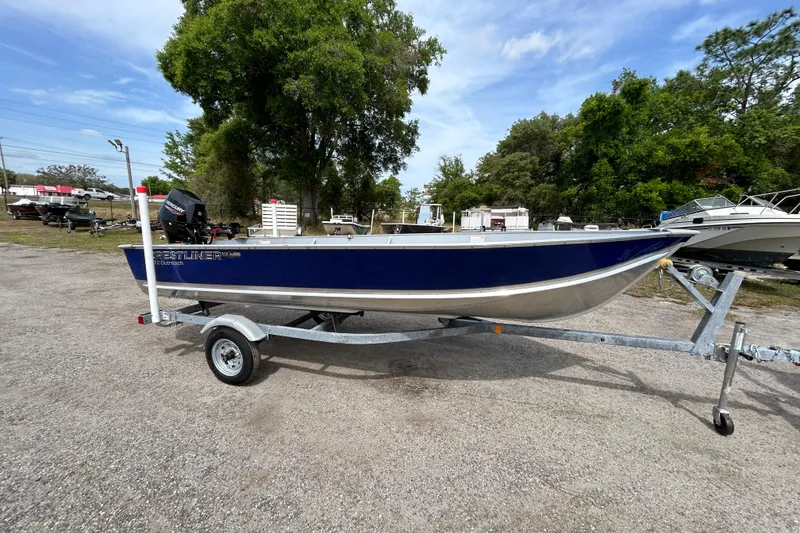 The Image of 2026 Crestliner 1672 Outreach boat on trailer, parked outdoors with trees in background. - 0