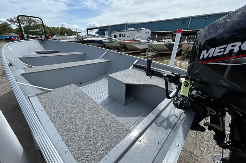 Slide: The Image of 2026 Crestliner 1672 Outreach boat with Mercury engine, parked outdoors near other boats. - 11