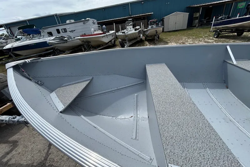 Slide: The Image of 2026 Crestliner 1672 Outreach boat interior, showcasing seating and storage, in a marina setting. - 14