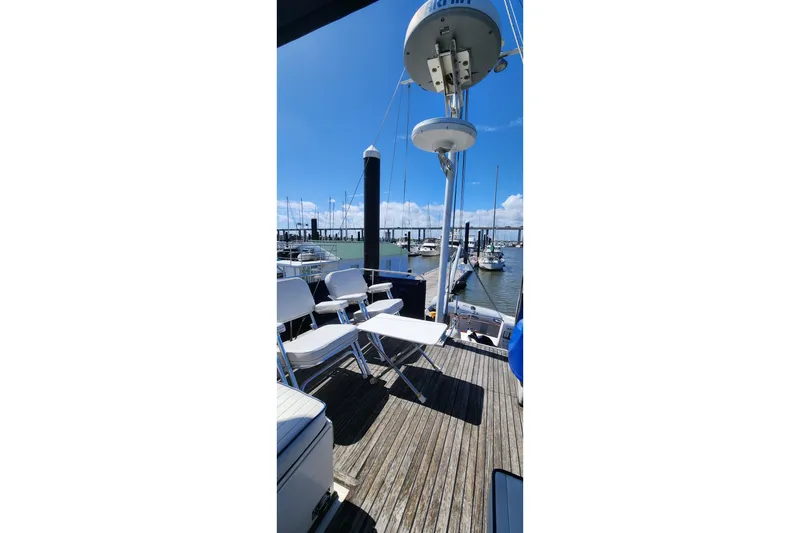 Slide: The Image of 1987 Grand Banks 36 Classic yacht deck with chairs, docked at marina under clear blue sky. - 11