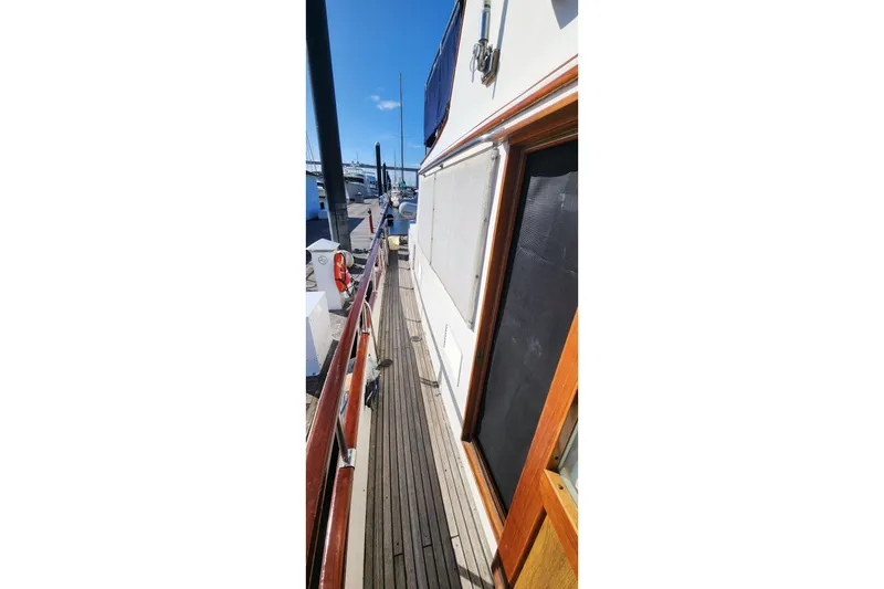 Slide: The Image of 1987 Grand Banks 36 Classic yacht deck with wooden railings and marina view. - 13