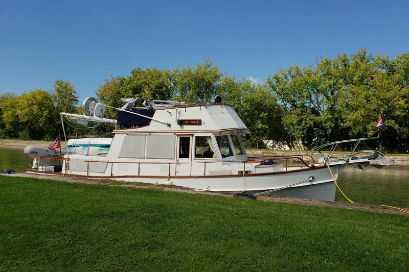 Slide: The Image of 1987 Grand Banks 36 Classic yacht docked by a scenic riverside. - 4