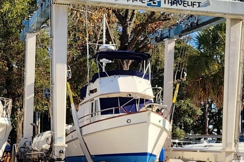 Slide: The Image of 1987 Grand Banks 36 Classic yacht in a boat lift, surrounded by trees. - 5