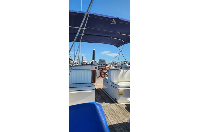 Slide: The Image of 1987 Grand Banks 36 Classic yacht interior with wooden steering wheel and blue canopy. - 9