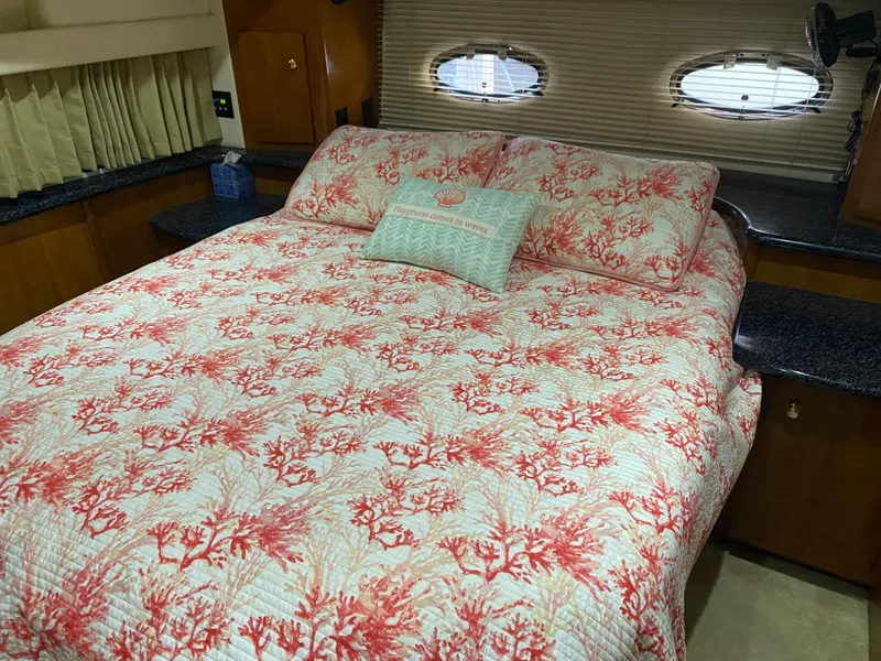 Slide: The Image of Carver 396 Motor Yacht 2000 bedroom with coral-themed bedding and porthole windows. - 23