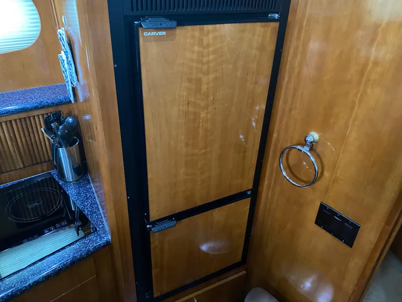 Slide: The Image of Carver 396 Motor Yacht 2000 kitchen area with wooden cabinetry and built-in refrigerator. - 34