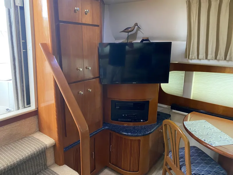 Slide: The Image of Interior of 2000 Carver 396 Motor Yacht with TV, wooden cabinets, and dining area. - 37