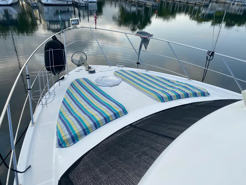 Slide: The Image of 2000 Carver 396 Motor Yacht with striped sun pads on the bow, docked at a marina. - 7