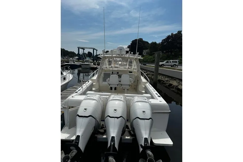 The Image of 2004 Intrepid 377 Walkaround boat with triple outboard engines docked at marina. - 1