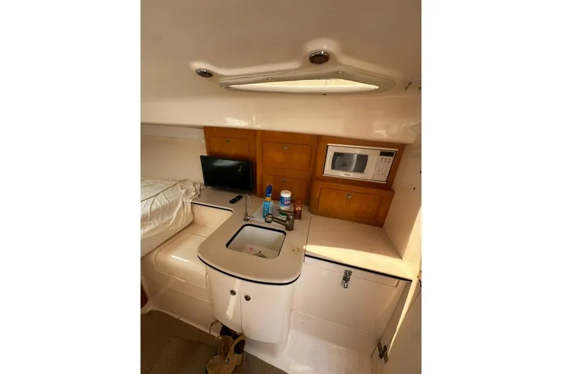 Slide: The Image of 2004 Intrepid 377 Walkaround cabin with kitchenette, sink, microwave, and storage cabinets. - 11