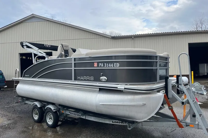 The Image of 2023 Harris Cruiser 190 pontoon boat on trailer outside warehouse. - 1
