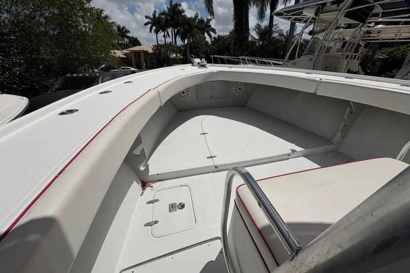 Slide: The Image of 2002 Ocean Runner 30 boat interior with white seating and red trim, surrounded by palm trees. - 10