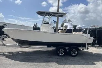 Slide: The Image of 2023 NauticStar 2302 Legacy boat on trailer, parked outdoors under a cloudy sky. - 5
