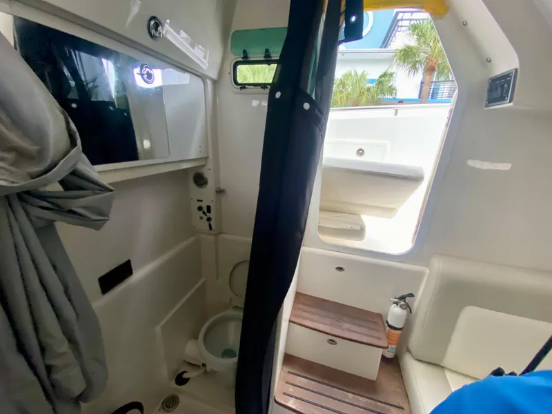 Slide: The Image of Interior of 2016 Everglades 435 Center Console boat, featuring compact bathroom and wooden steps. - 22