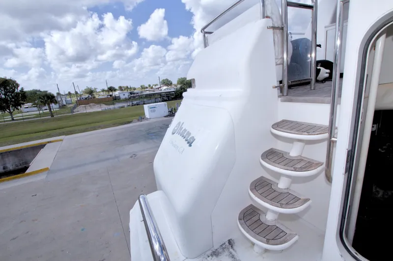 Slide: The Image of Staircase on 1998 Lazzara 76 Skylounge Grand Salon yacht, docked under a cloudy sky. - 103