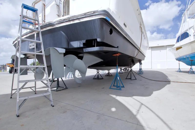Slide: The Image of Lazzara 76 Skylounge Grand Salon yacht, 1998, on dry dock with visible propellers and ladder. - 124