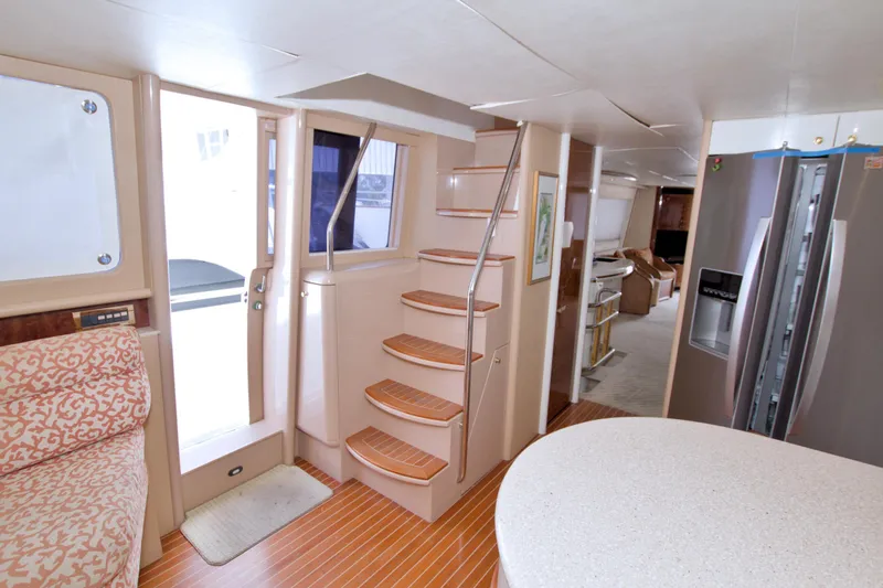 Slide: The Image of Interior of 1998 Lazzara 76 Skylounge Grand Salon yacht, featuring stairs and modern kitchen area. - 51
