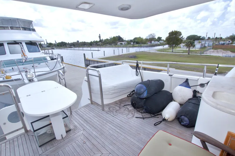 Slide: The Image of Deck view of 1998 Lazzara 76 Skylounge Grand Salon yacht docked by the water. - 7