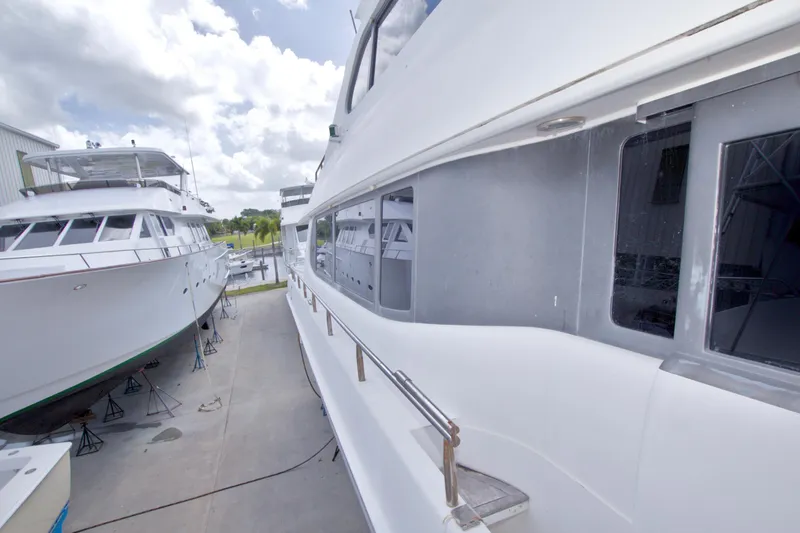 Slide: The Image of 1998 Lazzara 76 Skylounge Grand Salon yacht docked beside another vessel under a cloudy sky. - 70