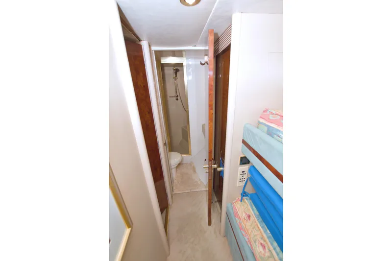 Slide: The Image of Narrow yacht bathroom with shower, bunk beds, and wooden door on 1998 Lazzara 76 Skylounge Grand Salon. - 99