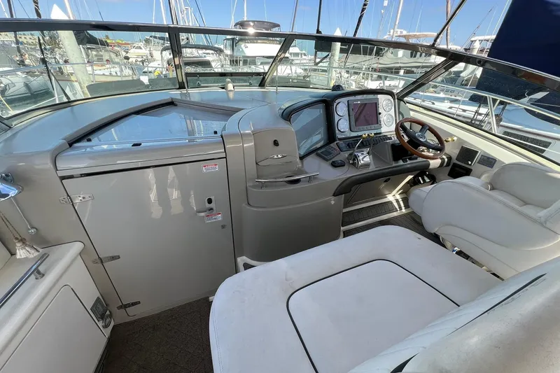 Slide: The Image of 2005 Sea Ray 390 Sundancer helm with navigation controls and seating in marina setting. - 12