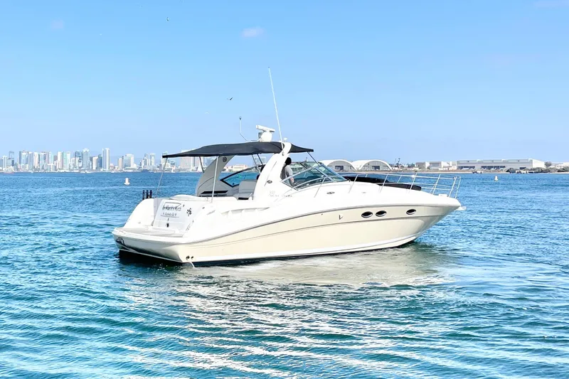 Slide: The Image of 2005 Sea Ray 390 Sundancer yacht cruising on blue water with city skyline backdrop. - 4