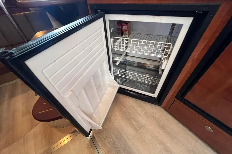 Slide: The Image of Open refrigerator inside 2005 Sea Ray 390 Sundancer yacht, showcasing interior storage space. - 41