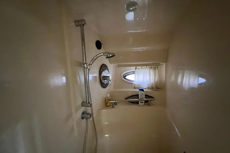 Slide: The Image of Shower area inside 2005 Sea Ray 390 Sundancer yacht, featuring a porthole and showerhead. - 55