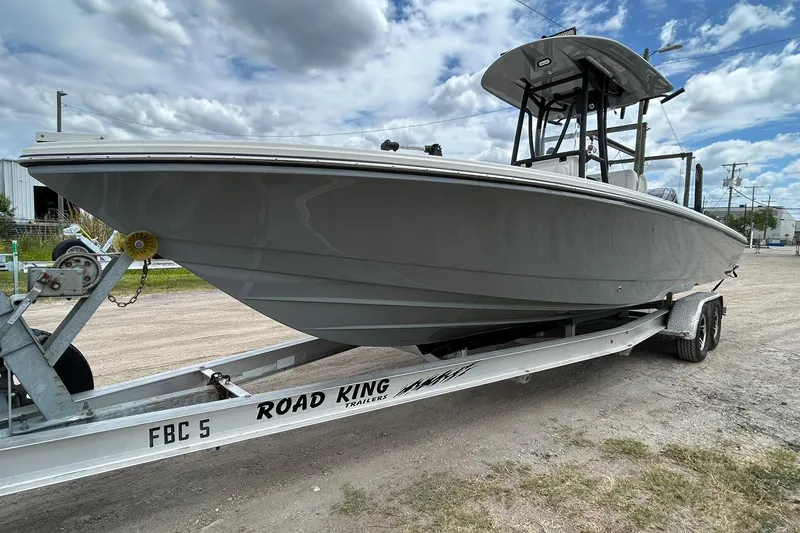 The Image of 2023 Pathfinder 2600 HPS boat on Road King trailer, parked outdoors under cloudy sky. - 0