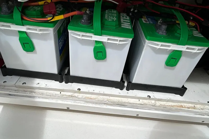 Slide: The Image of Three marine batteries in a 2023 Pathfinder 2600 HPS boat, secured with green straps. - 25