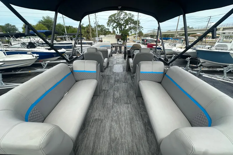 Slide: The Image of 2022 Qwest LTZ 824 pontoon boat interior with gray seating and blue accents at a marina. - 25